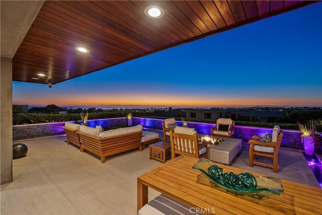 patio terrace at dusk with an outdoor living space with a fire pit