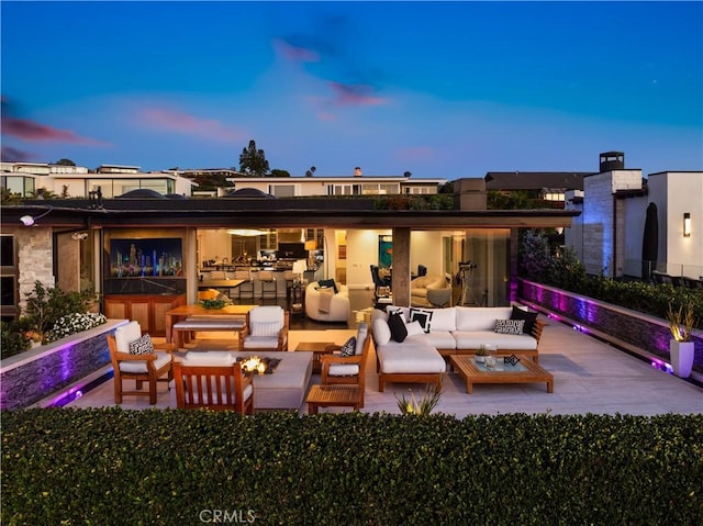 back house at dusk with an outdoor living space with a fire pit and a patio