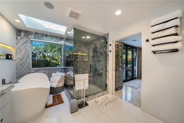 bathroom featuring independent shower and bath, tile walls, a wealth of natural light, and a skylight