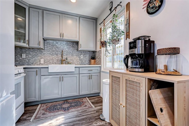 kitchen with gray cabinetry, sink, dark hardwood / wood-style flooring, white range oven, and decorative backsplash