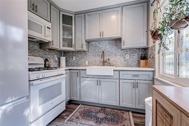 kitchen with tasteful backsplash, white appliances, dark wood-type flooring, sink, and gray cabinets