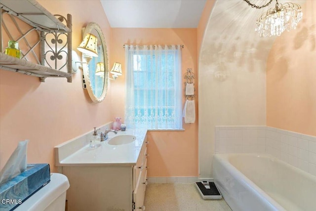 bathroom with vanity, toilet, a bathing tub, and a notable chandelier