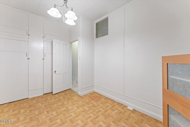 interior space featuring light parquet floors and a notable chandelier