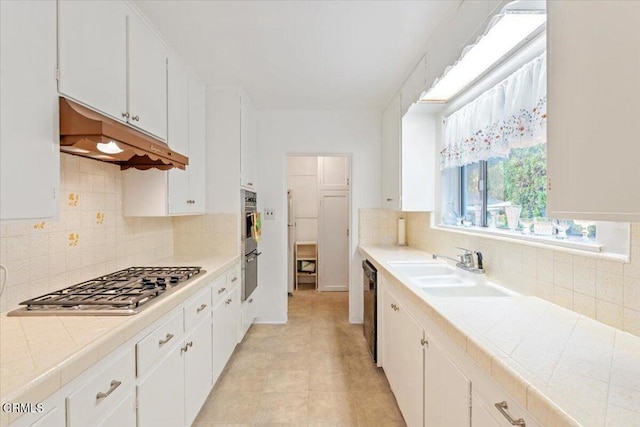 kitchen with sink, tile counters, white cabinets, and appliances with stainless steel finishes