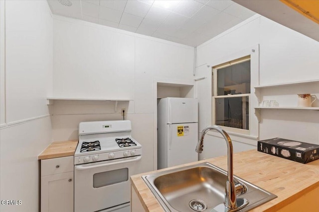 kitchen featuring butcher block countertops, white cabinets, white appliances, and sink