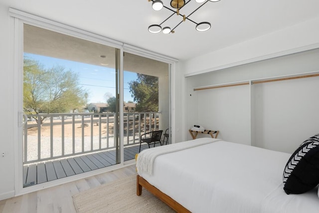 bedroom with access to exterior, a closet, a notable chandelier, and hardwood / wood-style flooring