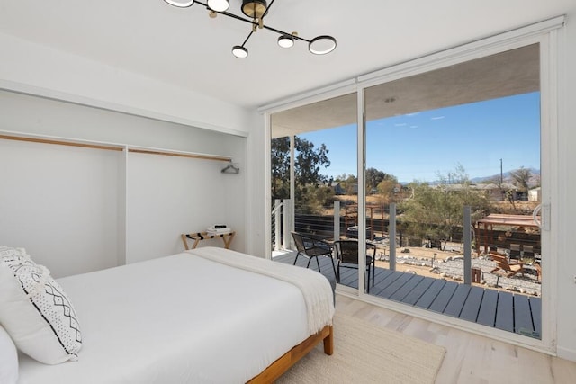 bedroom featuring a chandelier, hardwood / wood-style floors, and access to outside