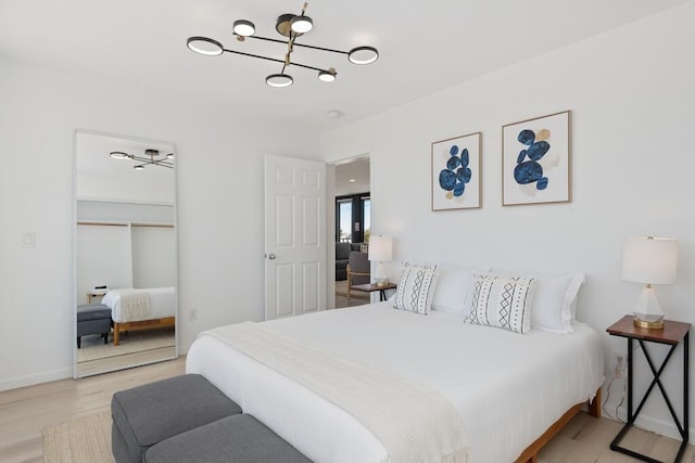 bedroom with a chandelier and light wood-type flooring