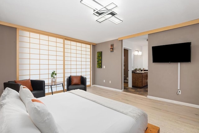 bedroom with ensuite bathroom and hardwood / wood-style flooring