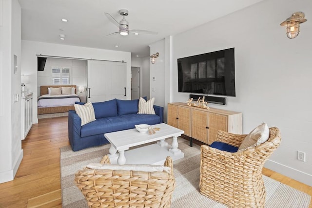 living room with recessed lighting, a barn door, wood finished floors, and a ceiling fan