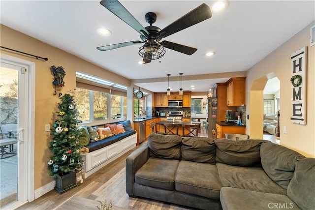 living room featuring ceiling fan, sink, and light hardwood / wood-style floors