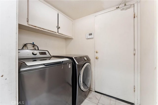 clothes washing area featuring washing machine and dryer and cabinets