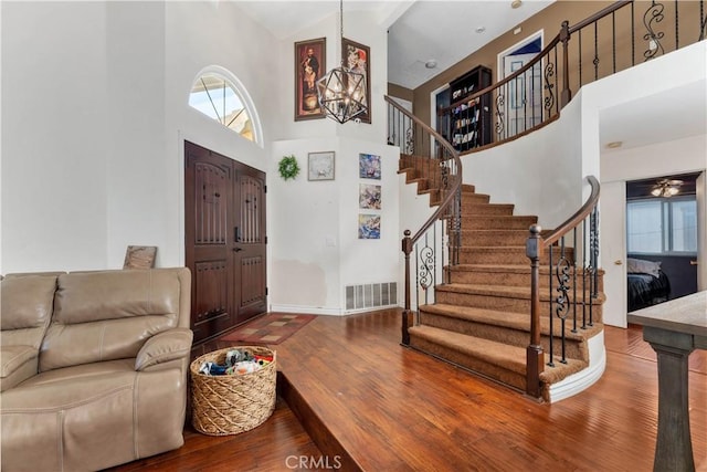 foyer featuring wood-type flooring, high vaulted ceiling, and a notable chandelier