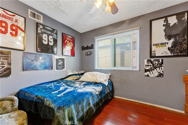 bedroom featuring a textured ceiling, dark hardwood / wood-style floors, and ceiling fan