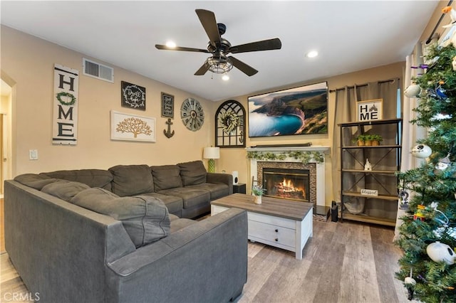 living room with a high end fireplace, hardwood / wood-style floors, and ceiling fan