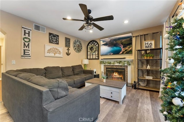 living room with a fireplace, light hardwood / wood-style flooring, and ceiling fan