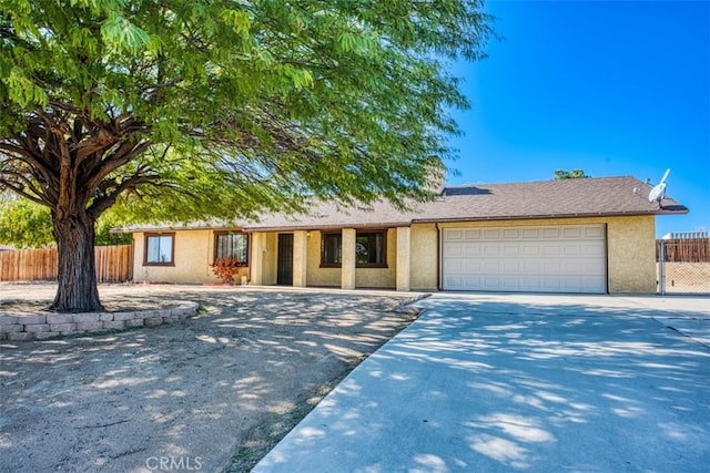 ranch-style home with stucco siding, concrete driveway, a garage, and fence