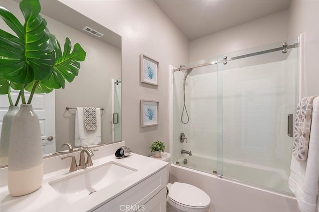 full bathroom with combined bath / shower with glass door, vanity, and toilet