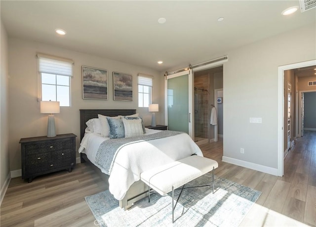 bedroom featuring hardwood / wood-style flooring and a barn door