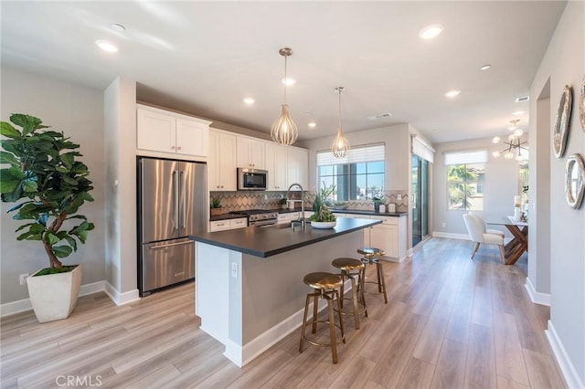 kitchen featuring white cabinetry, a center island, hanging light fixtures, premium appliances, and light hardwood / wood-style floors