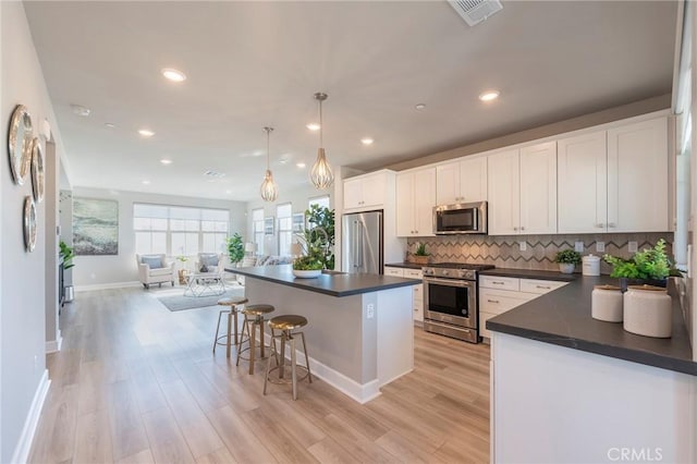 kitchen featuring white cabinets, pendant lighting, light hardwood / wood-style flooring, and high quality appliances