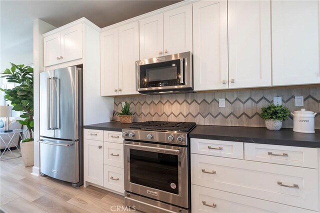 kitchen featuring white cabinetry, backsplash, high quality appliances, and light wood-type flooring