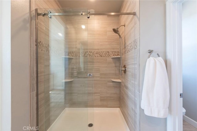 bathroom with a shower with shower door and toilet