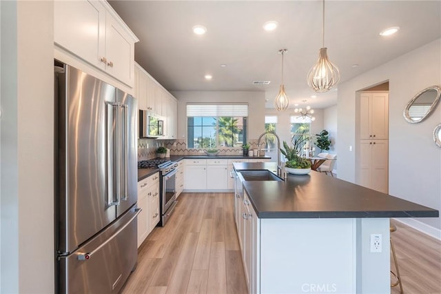 kitchen featuring white cabinetry, an island with sink, pendant lighting, light hardwood / wood-style floors, and high quality appliances