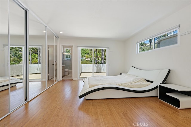 bedroom featuring access to exterior, light hardwood / wood-style flooring, connected bathroom, and multiple windows