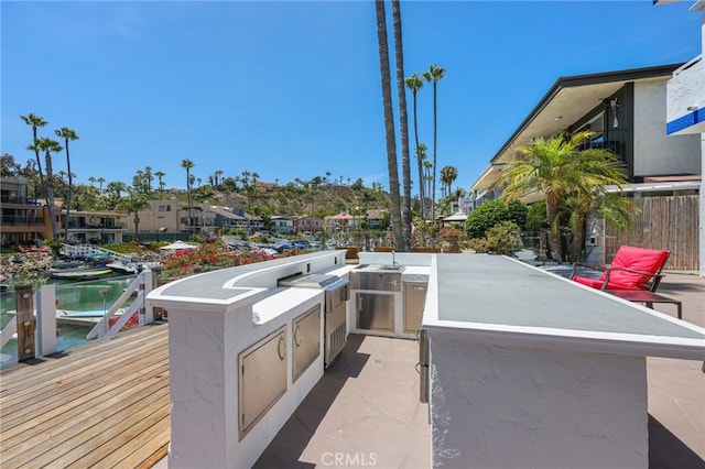 view of patio featuring a water view and exterior kitchen