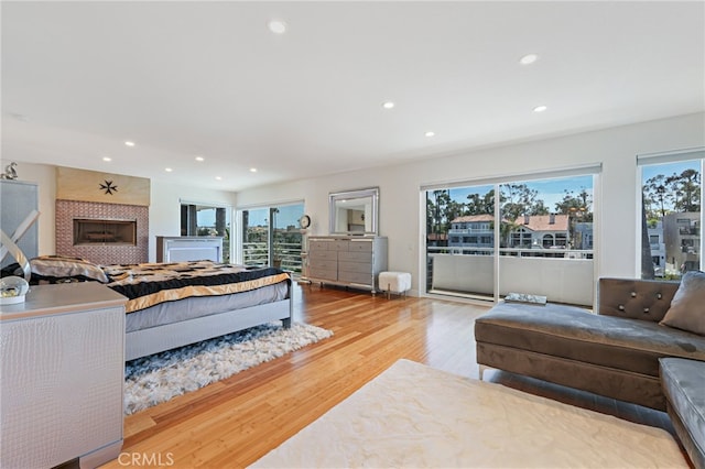 bedroom with a fireplace, access to outside, and light hardwood / wood-style flooring