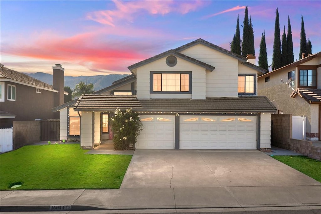 front facade featuring a lawn, a mountain view, and a garage