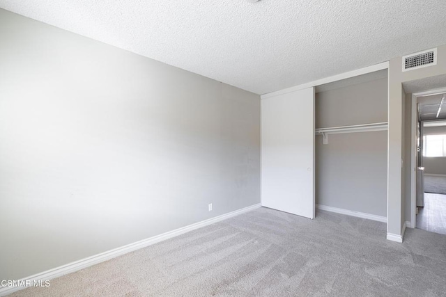 unfurnished bedroom featuring a textured ceiling, carpet floors, and a closet