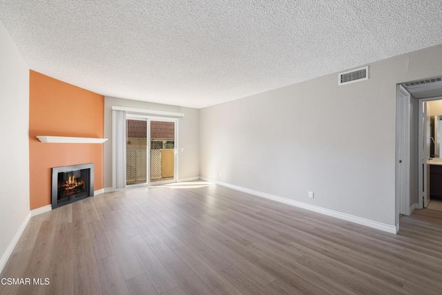 unfurnished living room with a textured ceiling and light hardwood / wood-style flooring