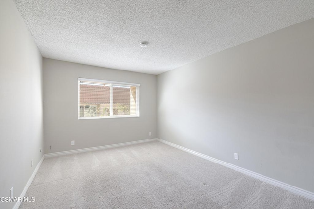 empty room with light colored carpet and a textured ceiling