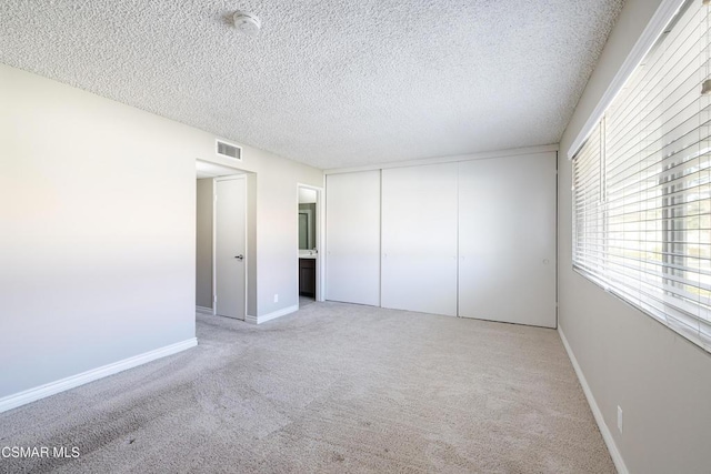 unfurnished bedroom featuring a closet, light colored carpet, and a textured ceiling