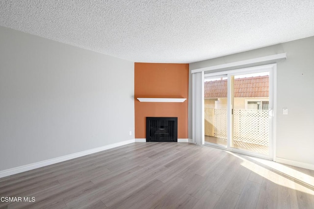 unfurnished living room with light hardwood / wood-style floors and a textured ceiling