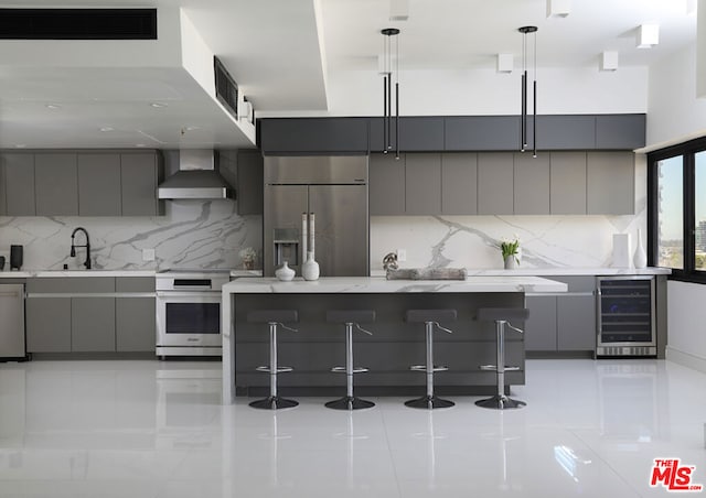 kitchen with pendant lighting, stainless steel appliances, wall chimney exhaust hood, and gray cabinetry