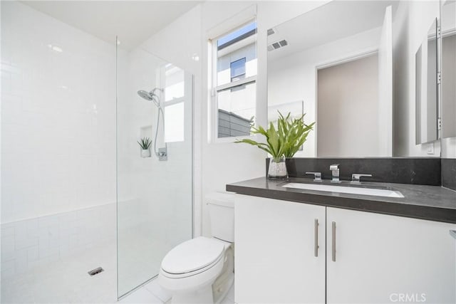 bathroom featuring tile patterned floors, vanity, toilet, and tiled shower