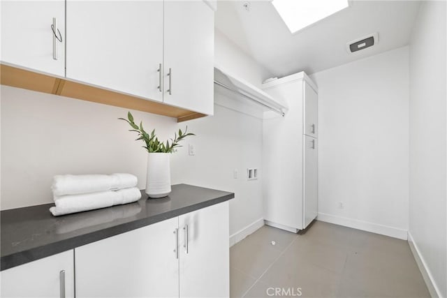 washroom with cabinet space, hookup for a washing machine, and baseboards