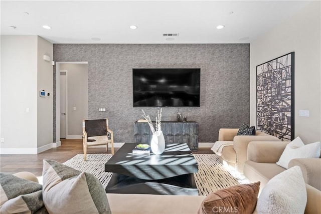 living room with recessed lighting, an accent wall, wood finished floors, visible vents, and baseboards