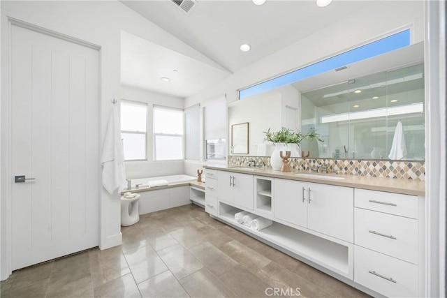 bathroom featuring vanity, lofted ceiling, backsplash, plus walk in shower, and tile patterned floors