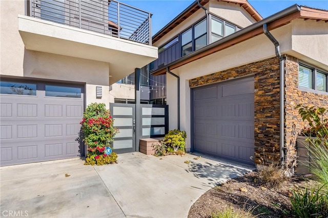 exterior space with stone siding, an attached garage, concrete driveway, and stucco siding