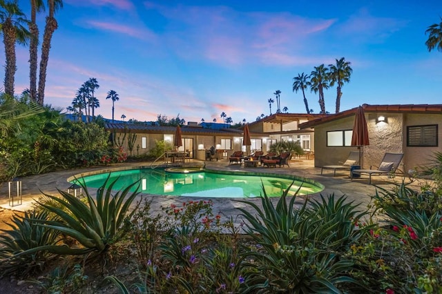 pool at dusk with a patio