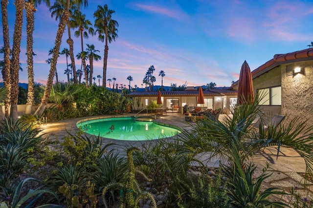 pool at dusk featuring a patio