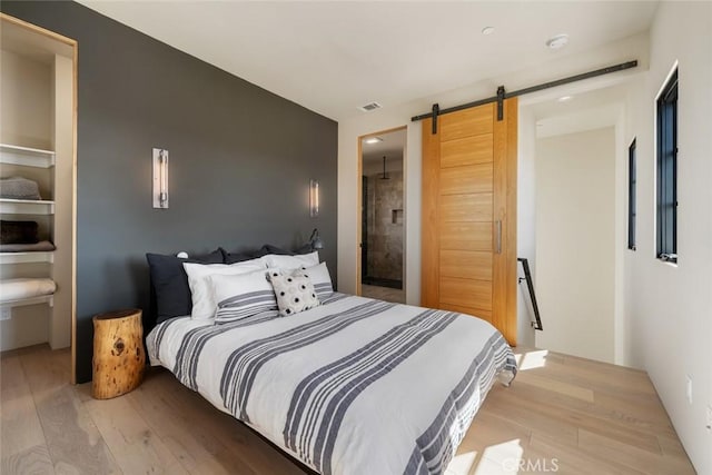 bedroom featuring a barn door and light hardwood / wood-style flooring