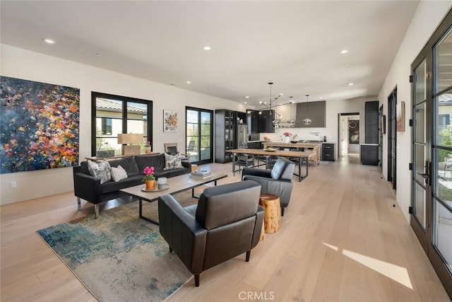 living room with light wood-type flooring and an inviting chandelier