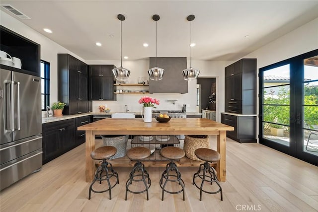 kitchen featuring wood counters, high end refrigerator, decorative light fixtures, and light hardwood / wood-style flooring