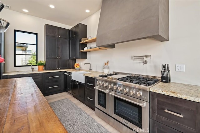 kitchen featuring wood counters, range with two ovens, and sink