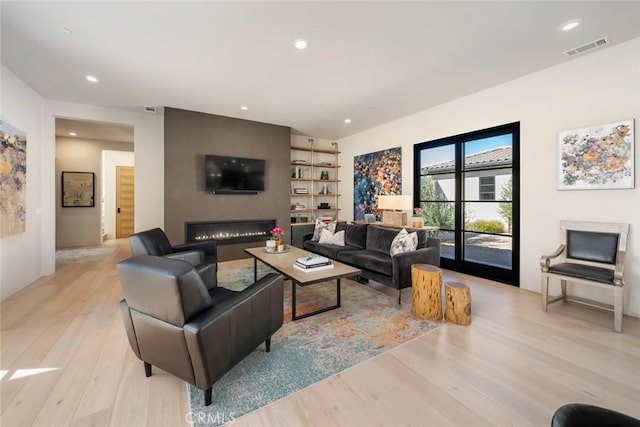 living room featuring light wood-type flooring and a large fireplace